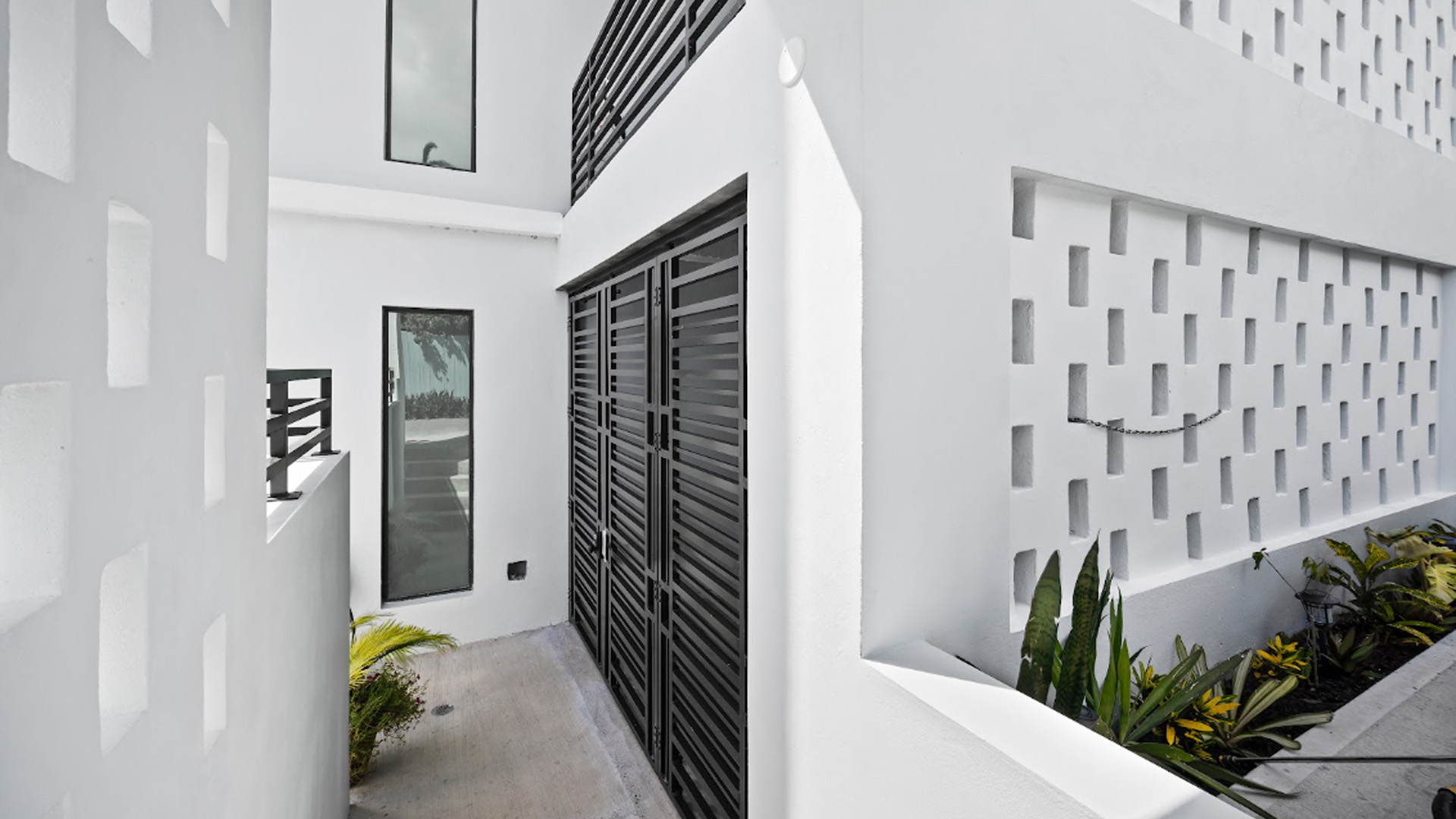Modern white interior hallway with geometric wall pattern and tropical plants